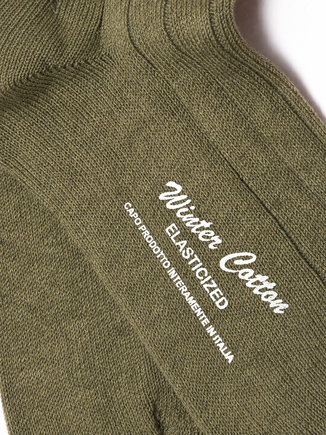 Close-up of olive green knit socks with white embroidered text reading 'Winter Cotton' and 'ELASTICIZED' on a white background. socks, cotton socks, high-knee socks, made in italy, handmade, artigianally made, fatto a mano, calzettoni invernali, winter cotton, calze di cotone, calze di cachemire, cachemire socks, cashmire socks